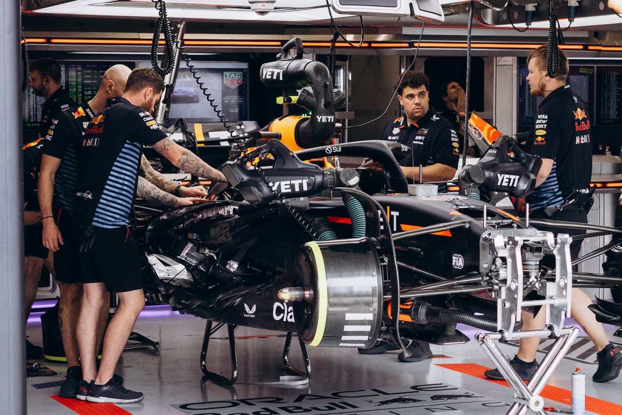 F1 mechanics work on a car in a garage. 