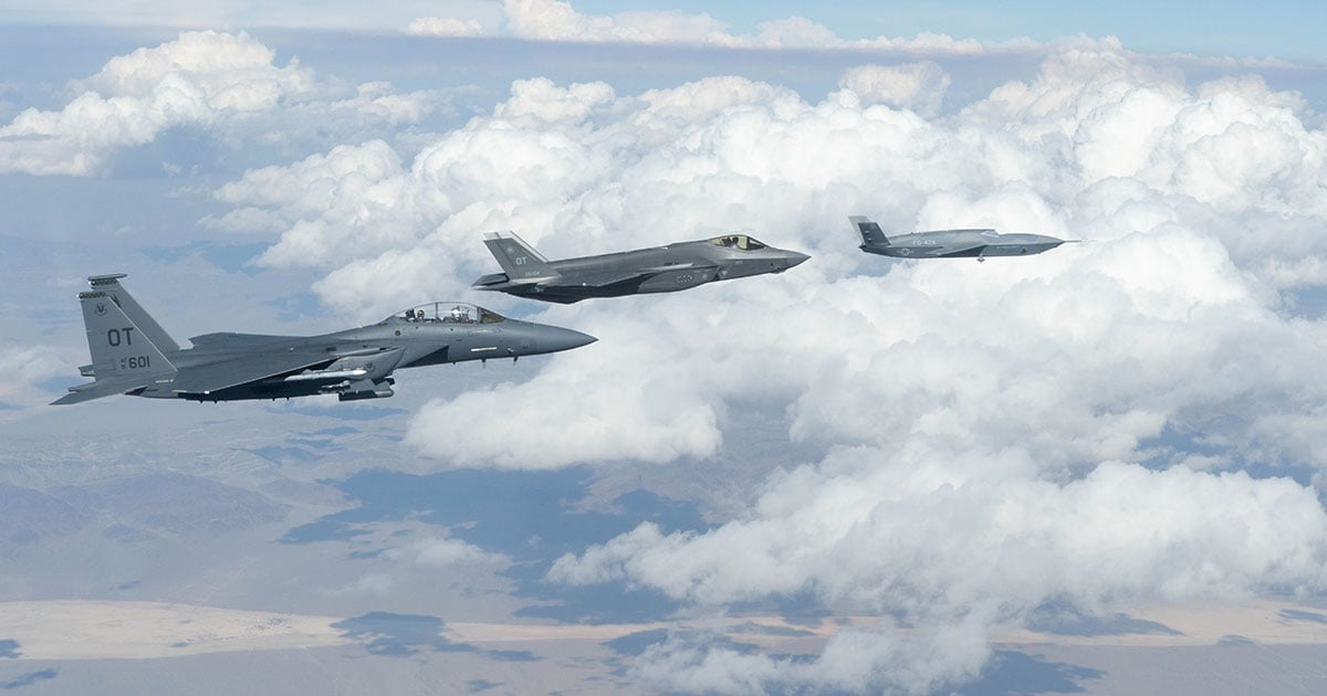 A General Atomics FQ-42 Vengeance  CCA  (right) flies in formation with a USAF F-35A and F-15E strike fighter.